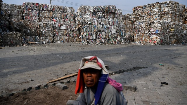 Seorang pekerja beraktivitas di dekat tumpukan sampah kertas yang diimpor oleh sebuah perusahaan pabrik kertas sebagai bahan baku kertas di Mojokerto, Jawa Timur, Rabu (19/6). Foto: ANTARA FOTO/Zabur Karuru