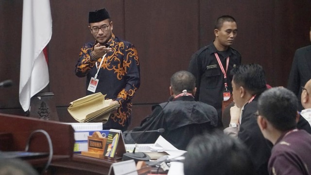 Komisioner KPU, Hasyim Asy'ari (kiri) membawa amplop C1 untuk diserahkan kepada hakim Mahkamah Konstitusi di Gedung Mahkamah Konstitusi, Jakarta, Kamis (20/6). Foto: Fanny Kusumawardhani/kumparan