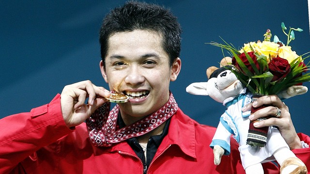 Taufik Hidayat menggigit mendali emasnya usai menjuarai bulutangkis tunggal putra di Asian Games ke-15 di Doha. Foto: AFP/LAURENT FIEVET