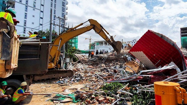 Sejumlah petugas dibantu alat berat membersihkan puing-puing bangunan yang runtuh di Sihanoukville, Kamboja. Foto: AFP/Ly LAY