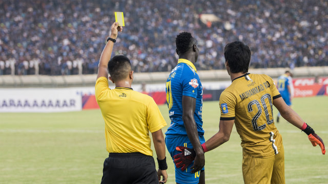 Wasit Aprisman Aranda (kiri) memberikan kartu kuning kepada pesepak bola Persib Bandung Ezechiel Ndouasel (tengah) didampingi penjaga gawang Madura United M Ridho. Foto: ANTARA FOTO/M Agung Rajasa