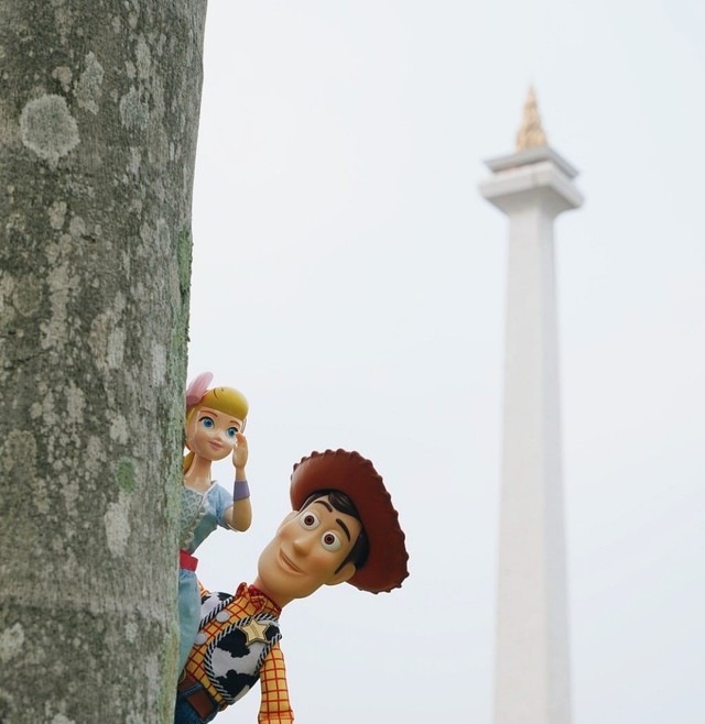Woody dan Bo Peep bersembunyi di belakang pohon di sekitar Monas