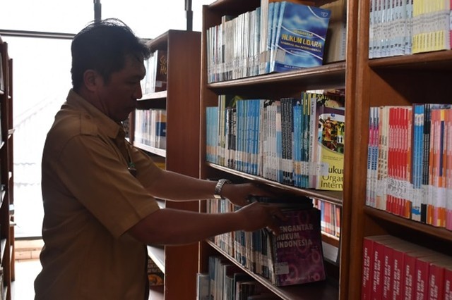 Pegawai Dinas Perpustakaan dan Arsip Daerah Provinsi Sulawesi Utara merapikan rak buku di Perpustakaan Daerah yang ada di Kota Manado. (foto: isa anshar jusuf)