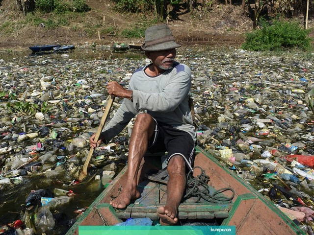 Seorang pria mendayung perahu kayunya untuk mengumpulkan sampah plastik untuk didaur ulang di sungai Citarum tersumbat oleh sampah dan limbah industri, di Bandung, Jawa Barat, Rabu (26/6). Foto: Timur Matahari / AFP