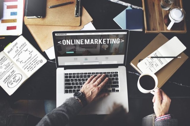 kerja dari rumah di laptop menjadi marketing online dan memegang cangkir kopi