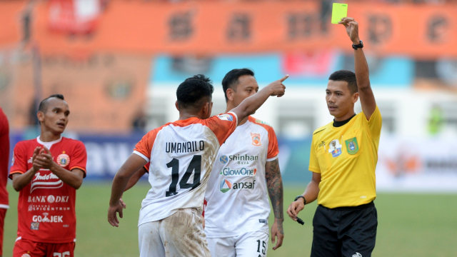 Wasit Wawan Rapiko (kanan) memberikan kartu kuning kepada pemain Borneo FC  Abrizal Umanailo dalam pertandingan semifinal leg pertama Piala Indonesia di Stadion Wibawa Mukti, Cikarang. Foto: ANTARA FOTO/M Risyal Hidayat