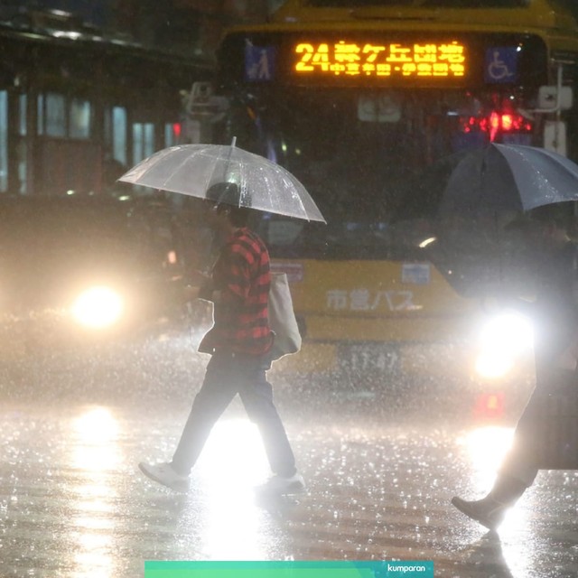 Warga berjalan di tengah hujan lebat di pusat kota Kagoshima. Foto: AFP/JIJI PRESS