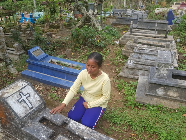 Salah seorang warga saat berada di makam desa Wirotaman, Kecamatan Tirtoyudho, Kabupaten Malang. Tampak, makam umat Kristiani dan umat Islam berdempetan.(foto: Irham Thoriq/Tugu Malang).