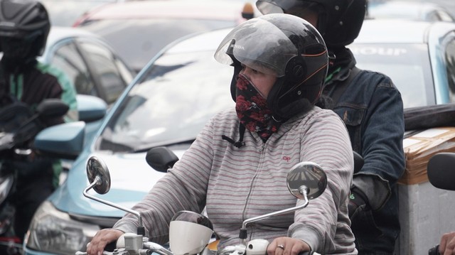 Seorang pengendara yang menggunakan masker saat mengendarai motor di kawasan Jakarta. Foto: Iqbal Firdaus/kumparan