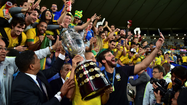 Alisson Becker mengabadikan momen Brasil juara Copa America 2019 dengan ponselnya. Foto: Luis ACOSTA / AFP