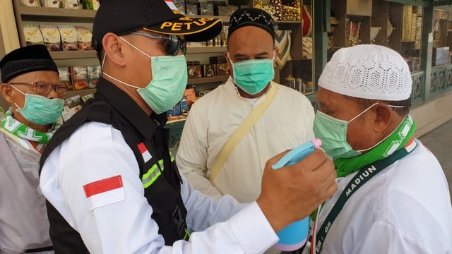Petugas haji menyemprot air ke wajah jemaah Indonesia di Masjid Nabawi, Madinah, untuk mengurangi panas.