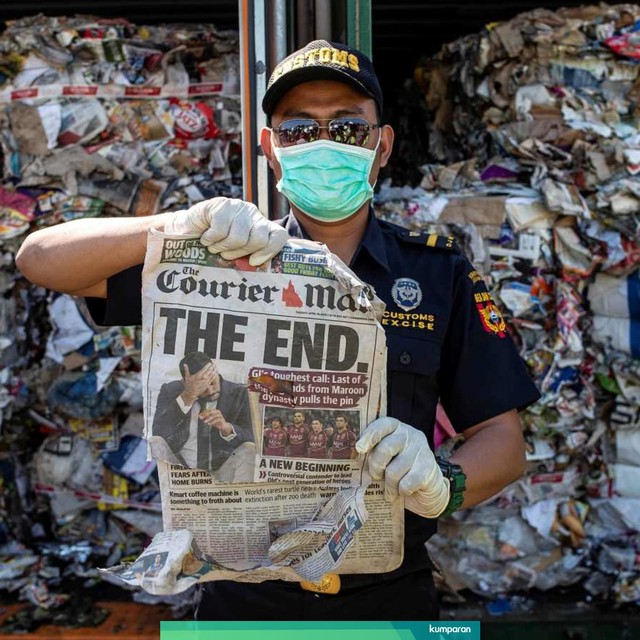 Seorang petugas bea cukai menunjukan kertas koran dari sebuah kontainer berisi sampah yang berasal dari Australia, Surabaya (9/7). Foto: AFP/Juni Kriswanto