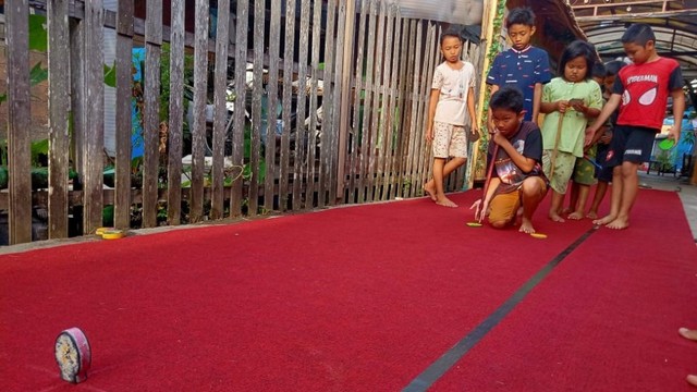 Anak-anak sibuk bermain Balogo di Gang Pendamai, Kelurahan Teluk Tiram, Kota Banjarmasin pada Rabu (10 Juli 2019. Foto: Donny Muslim/banjarhits.id