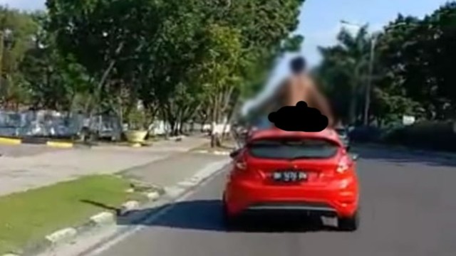 ORANG diduga gila telanjang bulat menari-nari di atas mobil sedang melaju di Jalan Sudirman, Pekanbaru, Kamis, 11 Juli 2019. 
