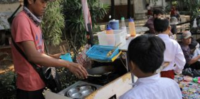 Seorang pedagang menjajakan dagangannya kepada siswa sekolah dasar. Foto: Jamal Ramadhan/kumparan