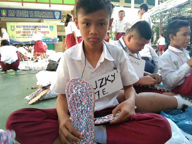 Seorang siswa sedang memamerkan sandal berbahan dasar sampah plastik. (Tara Wahyu N.V.)