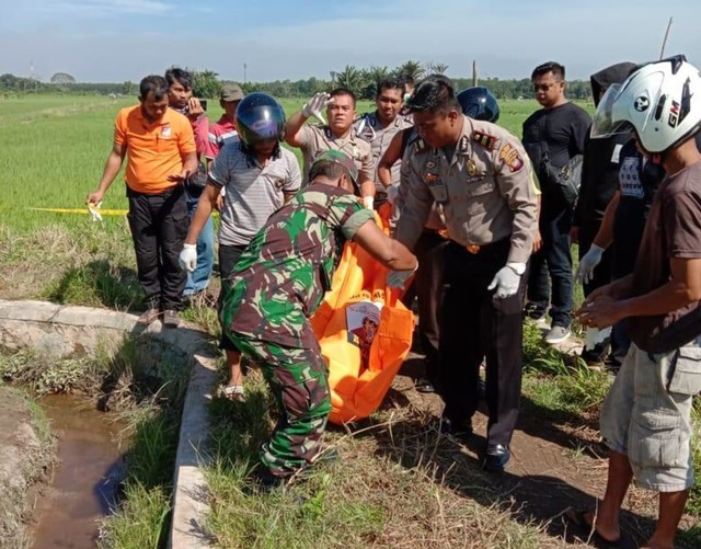 Personel polisi dan TNI mengevakuasi jasad JS< seorang ibu rumah tangga yang ditemukan tewas di saluran irigasi sawah di Anjongan, Kabupaten Mempawah. Foto: Dok Hi!Pontianak