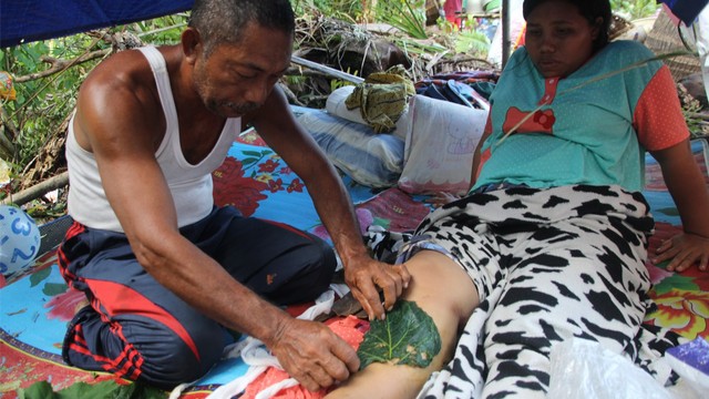 Yanti Haer, korban gempa yang patah tulang kaki kanan, mendapat pengobatan tradisional saat mengungsi di hutan. Foto: Faris Bobero/cermat.