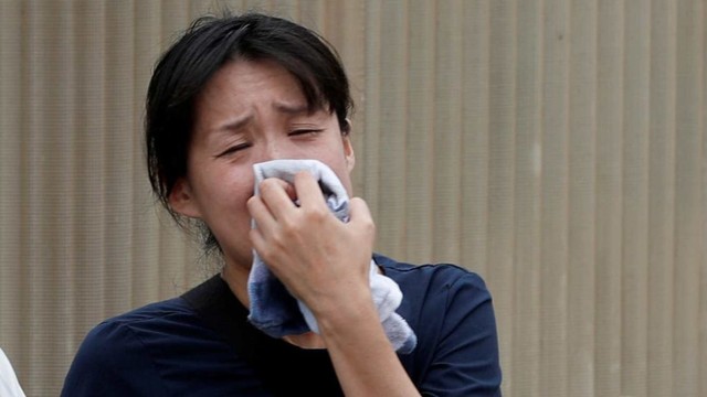 Seorang wanita menangis ketika melihat gedung Animasi Kyoto yang dibakar di Kyoto, Jepang. Foto: REUTERS/Kim Kyung-Hoon