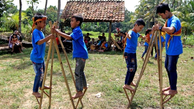 Anak-anak bermain permainan tradisional egrang di sawah Art Space, Desa Adat Kemiren, Banyuwangi, Jawa Timur. Foto: ANTARA FOTO/Budi Candra Setya