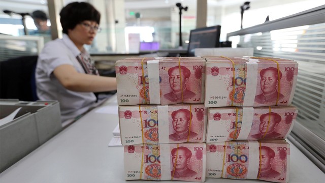 Seorang petugas bank meletakan mata uang kertas China, Renminbi. Foto: AFP