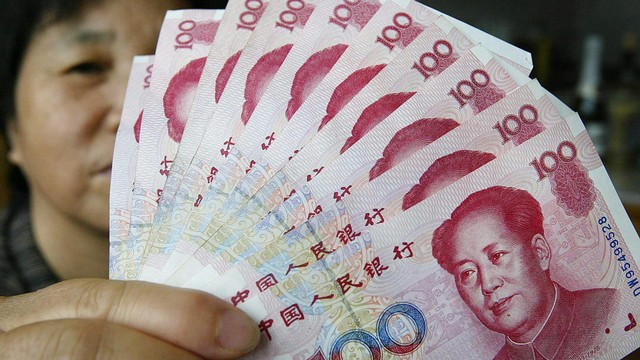 Seorang petugas menghitung uang kertas Renminbi. Foto: AFP