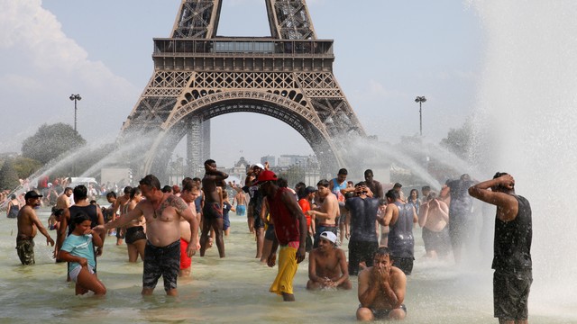 gelomWarga mendinginkan badan di air mancur Trocadero dekat Menara Eiffel, Paris, efek dari gelombang panas. Foto: Pascal Rossignol/Reuters