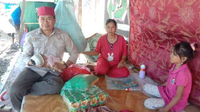 Wati (baju merah) bersama suami dan tiga anaknya harus rela tinggal di puing-puing kantor KPU Mamuju yang pernah terbakar. Foto: Awal Dion