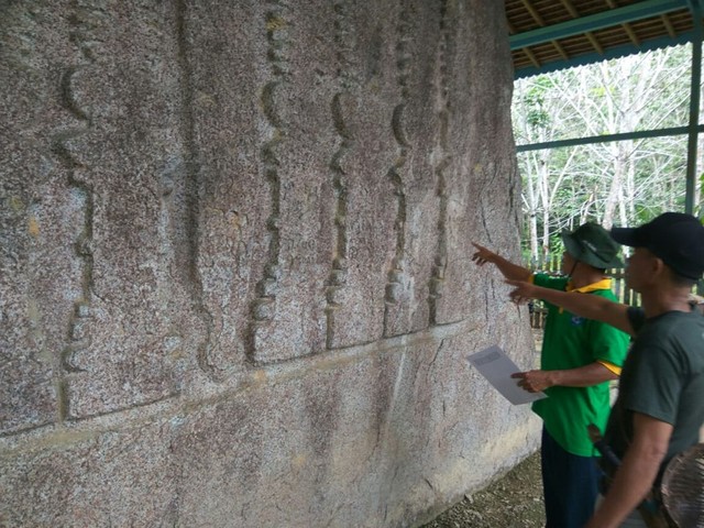 Petugas dari Dinas Pariwisata Sekadau bersama masyarakat setempat memantau Batu Bertulis. Foto: Dina Mariana/HiPontianak