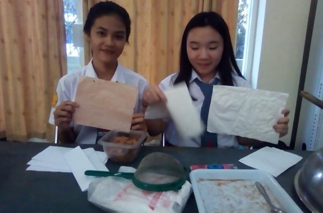 Firginia Oey dan Sabbathiny Rumampuk, siswa asal SMA Unklab Kabupaten Minahasa Utara, Sulawesi Utara, menunjukkan kertas antiair yang mereka buat berbahan dasar sabut kelapa, tepung tapioka, dan cat putih