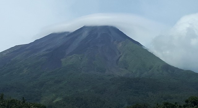 Gunung Karangetang di Kabupaten Siau Tagulandang Biaro (Sitaro), Sulawesi Utara, diselimuti oleh awan berbentuk topi. Fenomena ini diartikan warga sebagai pertanda akan terjadi gelombang atau ombak besar di perairan sulawesi