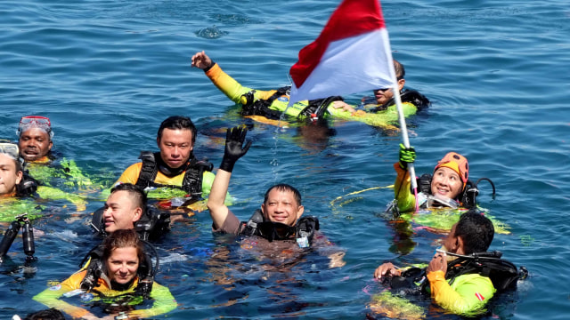 Kapolri Jendral Pol. Tito Karnavian (tengah) bersama istri Ny. Tri Tito Karnavian (mengibarkan bendera) saat naik ke permukaan usai penyelaman massal di kawasan pantai Megamas, Manado, Sulawesi Utara, Sabtu (3/8). Foto: ANTARA FOTO/Fisella Ruaw