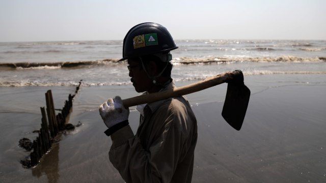 Petugas Oil Spill Combat Team (OSCT) menggunakan baju Tyvex, helmet, sarung tangan dan membawa cangkul saat membersihkan tumpahan minyak (Oil Spill) di Pesisir Pantai Sedari, Karawang. Foto: Aditia Noviansyah/kumparan