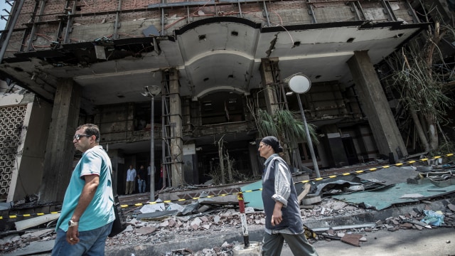 Warga Mesir berjalan di luar National Cancer Institute yang hancur akibat ledakan di Kairo, Mesir. Foto: AFP/KHALED DESOUKI