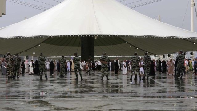 Para anggota pasukan keamanan Saudi berjaga-jaga ketika para jemaah tiba di Mina di bawah hujan lebat untuk melaksanakan lempar jumrah, Makkah, Senin (12/8) Foto: AFP/Abdel Ghani BASHIR