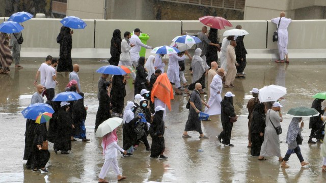 Para jemaah tiba di Mina di bawah hujan lebat untuk melaksanakan lempar jumrah, Makkah, Senin (12/8) Foto: AFP/FETHI BELAID