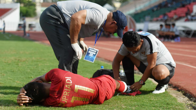 Pesepak bola Indonesia Supriadi (bawh) mendapat perawatan dari tim medis saat bertanding melawan Laos pada penyisihan Grup A Piala AFF U-18 2019 di Stadion Thong Nhat, Ho Chi Minh, Vietnam, Senin (12/8). Foto: ANTARA FOTO/Yusran Uccang