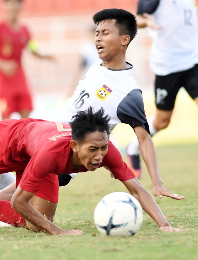 Pesepakbola Indonesia Beckham Putra Nugraha (kiri) terjatuh saat berebut bola dengan pesepakbola Laos Channichone saat bertanding pada penyisihan Grup A Piala AFF U-18 2019 di Stadion Thong Nhat, Ho Chi Minh, Vietnam, Senin (12/8). Foto: ANTARA FOTO/Yusran Uccang