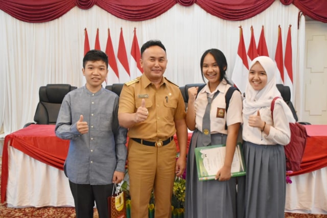 Gubernur Kalimantan Tengah Sugianto Sabran (kedua dari kiri) berfoto bersama para siswi peraih medali emas WICO dan Yazid selaku pencetus ide. (Foto: Diskominfo Kalteng)