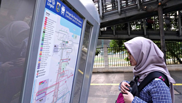 Seorang penumpang melihat informasi transportasi umum di Halte Gelora Bung Karno, Jakarta. Foto: Nugroho Sejati/kumparan