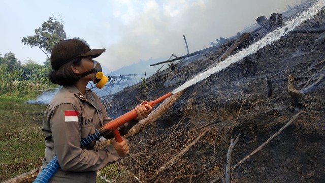 Seorang Polwan ikut memadamkan api yang membakar lahan di Entikong, Kalimantan Barat. Foto: Dok Polsek Entikong