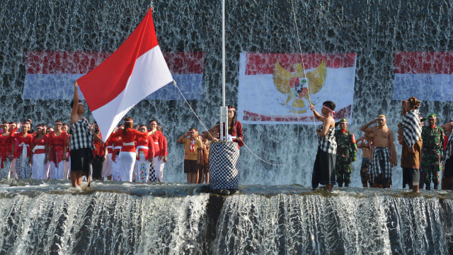 Warga yang mengenakan pakaian adat Bali mengibarkan Bendera Merah Putih dalam upacara bendera memperingati HUT ke-74 Proklamasi Kemerdekaan RI di Sungai Unda, Klungkung, Bali, Sabtu (17/8). Foto: ANTARA FOTO/Nyoman Budhiana