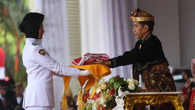 Presiden Joko Widodo (kanan) memberikan bendera kepada pembawa baki Paskibraka Salma El Mutafaqqiha Putri Achzaabi (kiri) dalam Upacara Peringatan Detik-Detik Proklamasi Kemerdekaan Indonesia ke-74 Tahun 2019 di Istana Merdeka, Jakarta, Sabtu (17/8). Foto: ANTARAFOTO/Akbar Nugroho Gumay