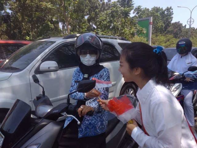 Yayasan Gege MeiMei Kalimantan Barat yang membagikan ratusan bendera merah putih kepada pengendara dan pengguna jalan. Foto: Lidya/Hi!Pontianak 