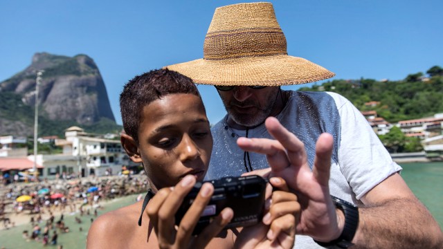 Fotografer AFP, Christophe Simon memberikan penjelasan kepada Marcio, seorang anak dari Cidade de Deus shantytown (favela), di Rio de Janeiro, Brasil, pada 26 Januari 2014. Foto: AFP/YASUYOSHI CHIBA