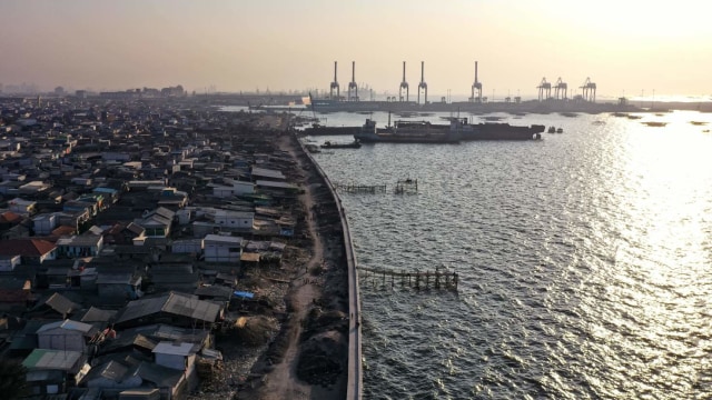 Foto udara yang menunjukkan tembok laut yang membelah rumah dan perairan di sepanjang pantai Jakarta Utara. Foto: AFP/BAGUS SARAGIH