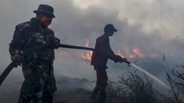 Petugas gabungan dari TNI dan Manggala Agni Daops Banyuasin berusaha memadamkan kebakaran lahan di Desa Pemulutan, Ogan Ilir, Sumatera Selatan, Jumat (23/8). Foto: ANTARA FOTO/Nova Wahyudi