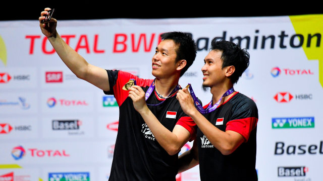 Ganda putra Indonesia Hendra Setiawan (kiri) dan Mohammad Ahsan berswafoto menunjukan medali emas usai Kejuaraan Dunia Bulu Tangkis 2019 di St. Jakobshalle, Basel, Swiss. Foto: ANTARA FOTO/Hafidz Mubarak