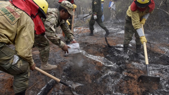 Tentara dan pemadam kebakaran berseragam kuning memadamkan api di hutan Amazon sekitar Robore, Bolivia timur. Foto: AFP/AIZAR RALDES