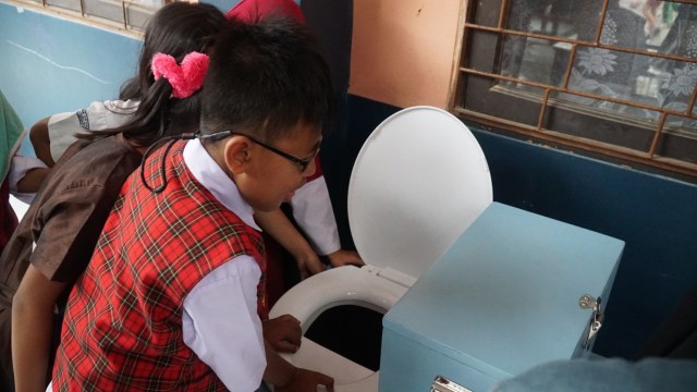 Siswa SD 210 Babakan Sinyar tengah melihat toilet kompos (Foto: Ananda Gabriel)